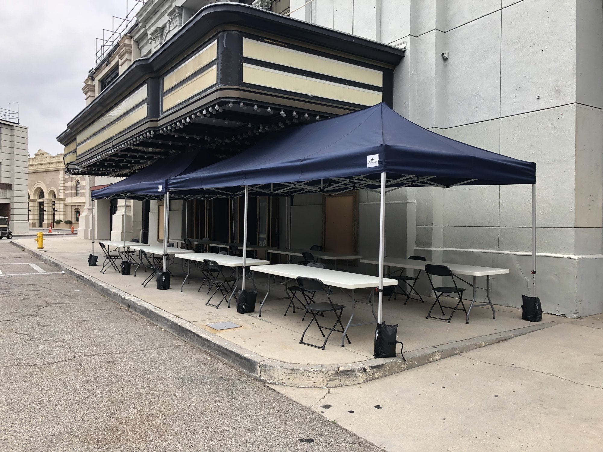 Navy Sunset tents with tables and chairs set up on a studio backlot sidewalk