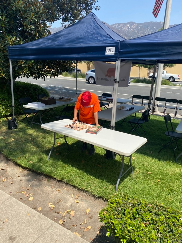Sunset navy canopy tent set up for a community charity chess event outdoors