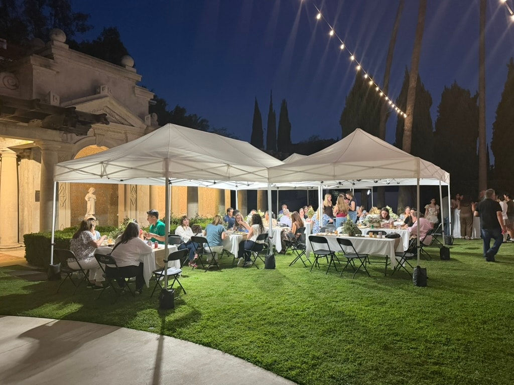 White Sunset tents at an evening garden event with string lights overhead