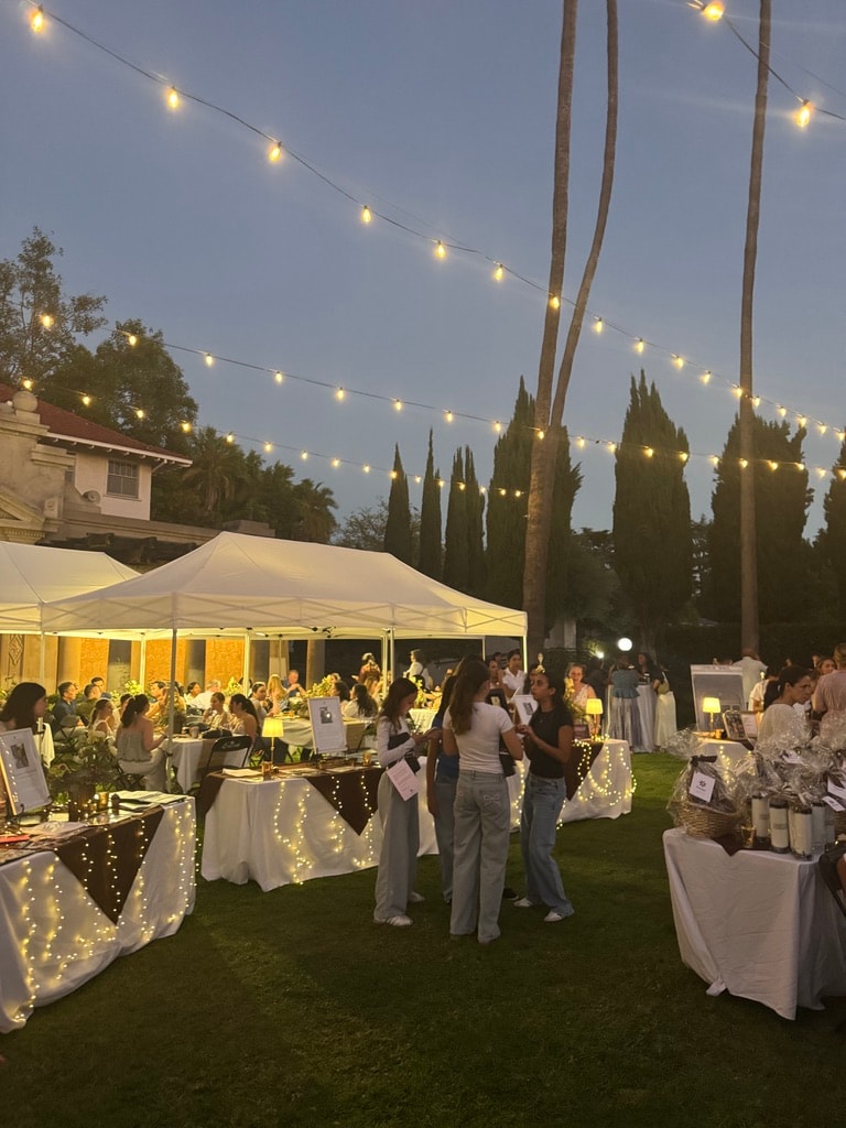Outdoor charity fundraiser event with white tents and string lights at dusk