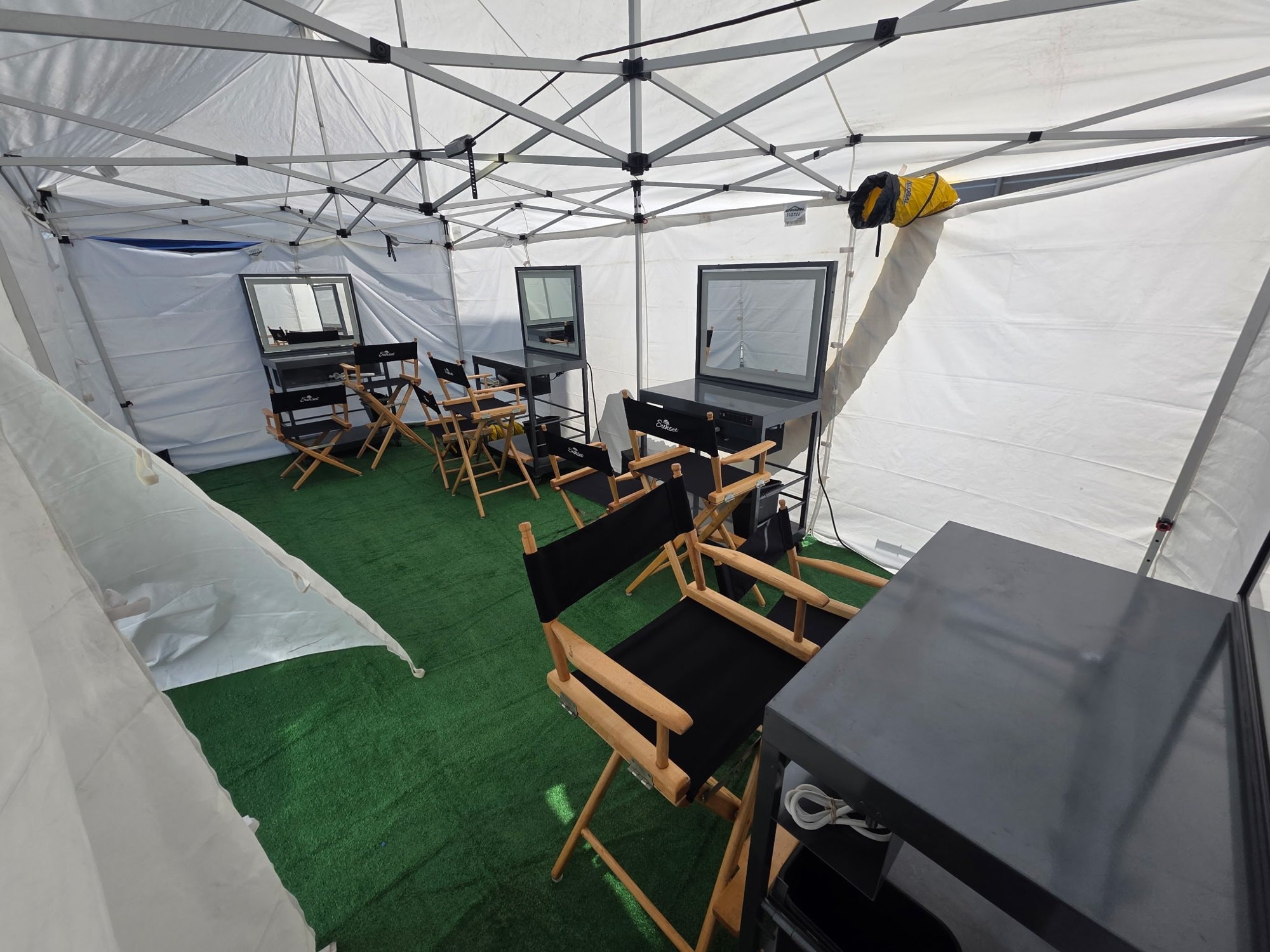 HMU tent with Sunset director chairs on set