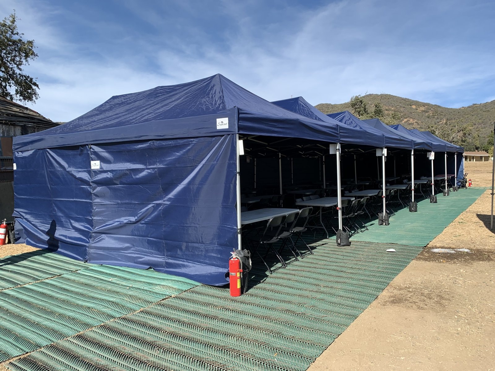 Sunset navy lunch tents with green ground protection on a hillside field