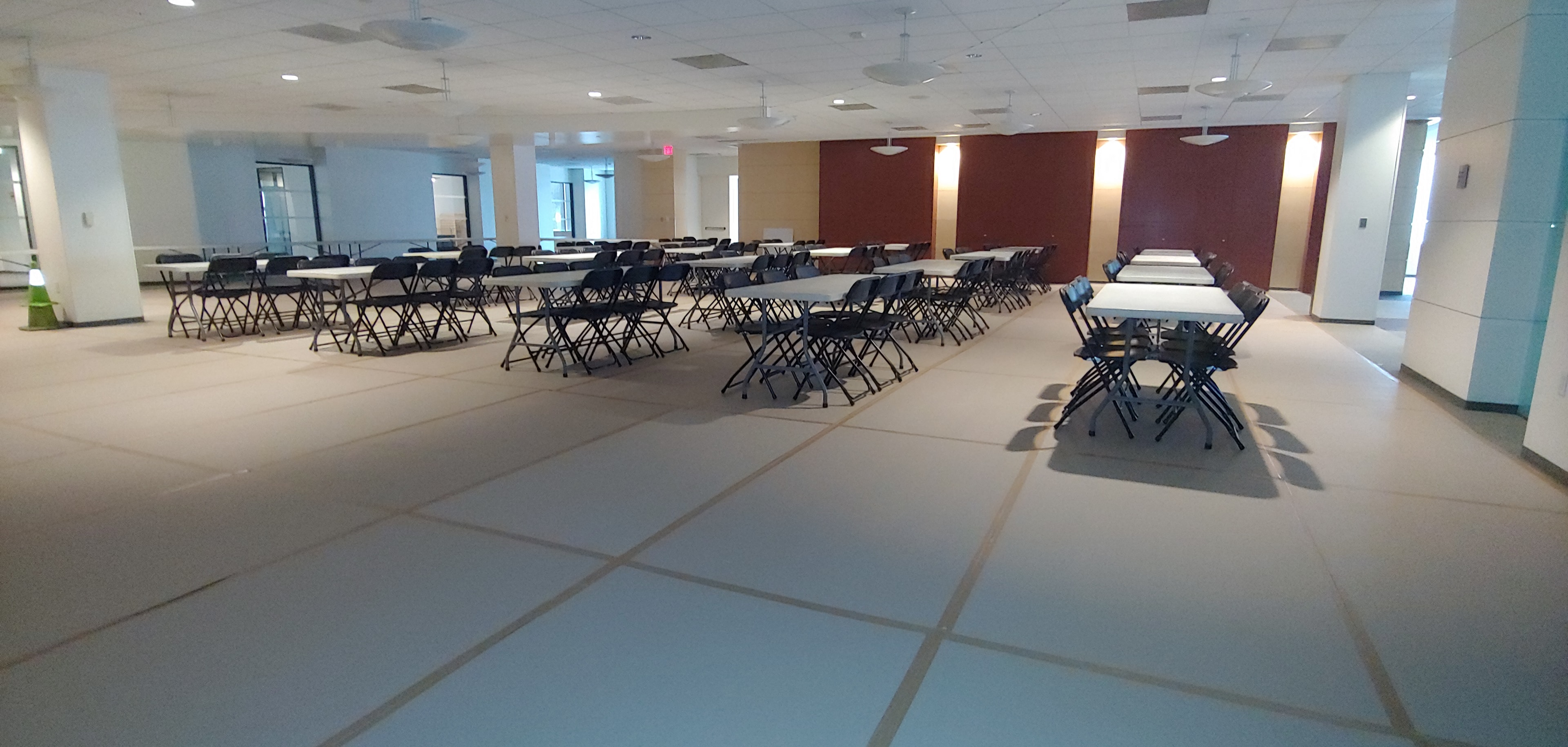 Indoor lunch setup with rows of tables and chairs on protected flooring