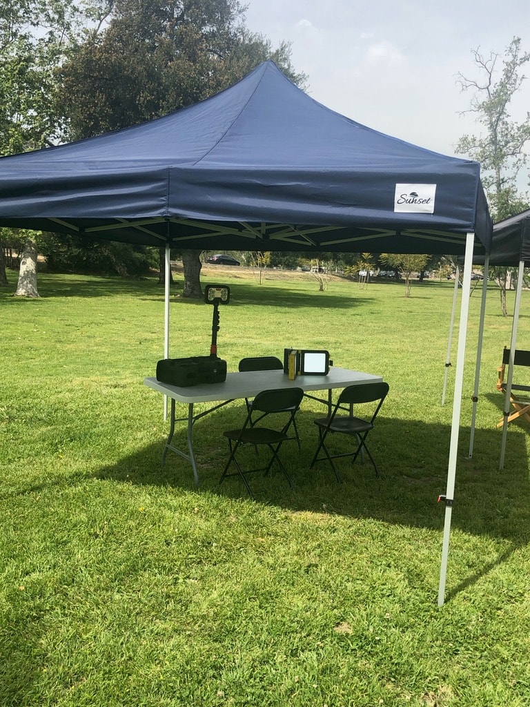 Navy Sunset tent with a makeup station table set up on a park lawn