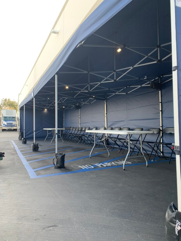 Inside a long navy Sunset tent run with tables and chairs lined up for a crew