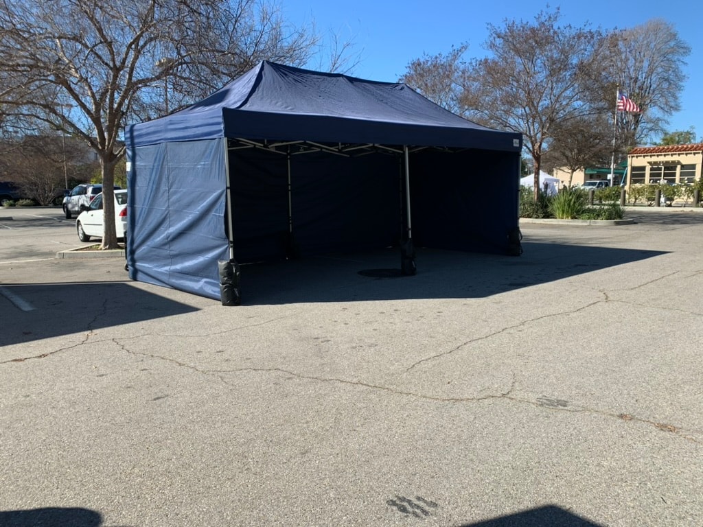 Large navy Sunset tent with full sidewalls set up in a parking lot
