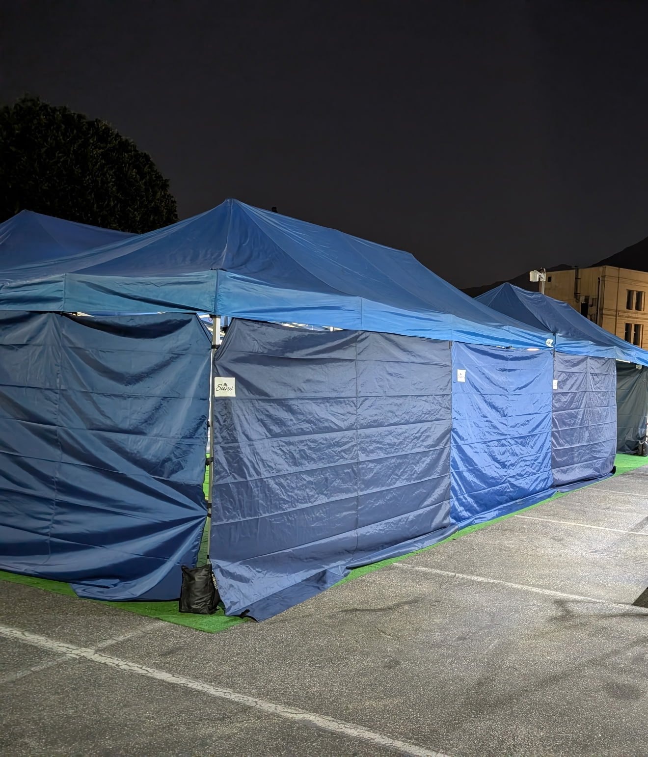 Row of navy Sunset tents lit up at night