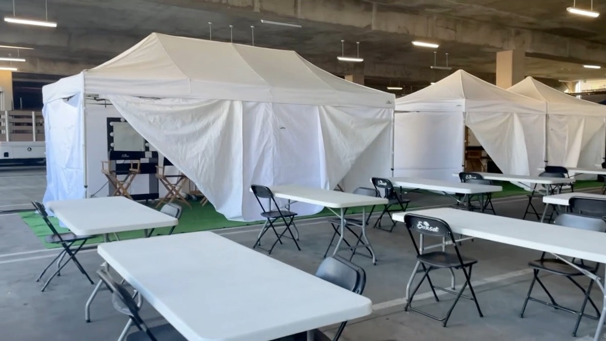 White hair and makeup tents with lunch tables set up in a parking structure