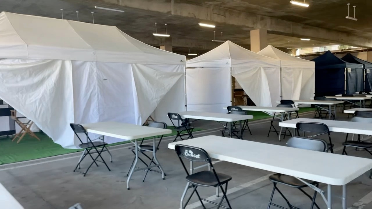 White and navy Sunset makeup tents with tables and chairs in a parking structure
