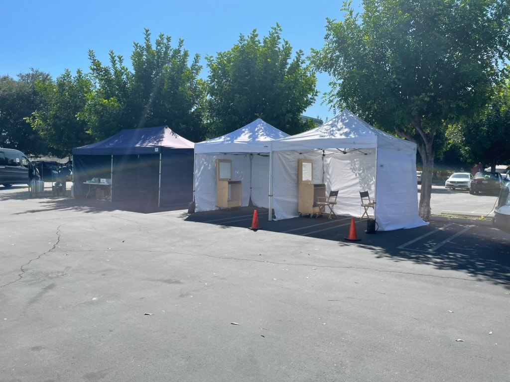 White and navy makeup tents set up in a parking lot on location